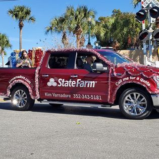 A red state farm truck is parked on the side of the road.