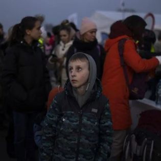 A boy in a camo jacket is standing in a crowd of people