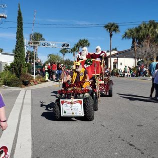 Santa claus is riding a four wheeler in a parade.