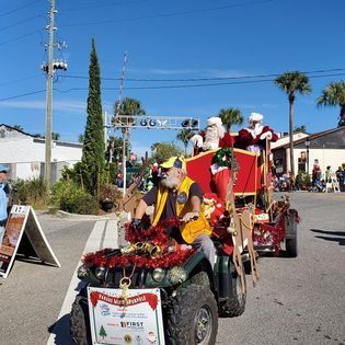 A man is riding on the back of a jeep in a parade.