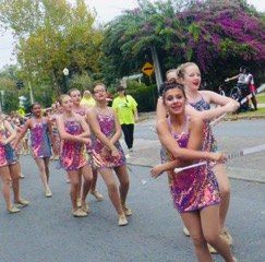 A group of young women are marching down a street in a parade.