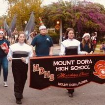 A group of people are marching down a street holding a banner.