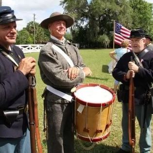 A group of men in military uniforms are standing next to a drum.