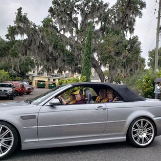 A group of people are sitting in a silver convertible car.