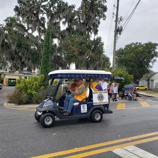 A group of people are riding in a golf cart on a street.