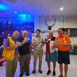 A group of men are standing next to each other holding money.