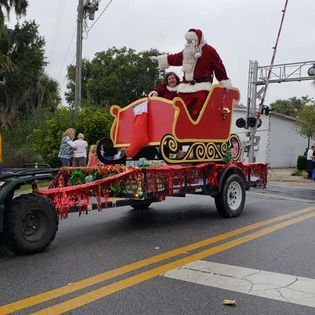 Santa claus is riding in a sleigh on a trailer.