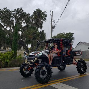A group of people are riding a monster truck down a street.