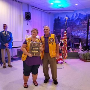 A man and a woman are standing next to each other in a room holding a plaque.