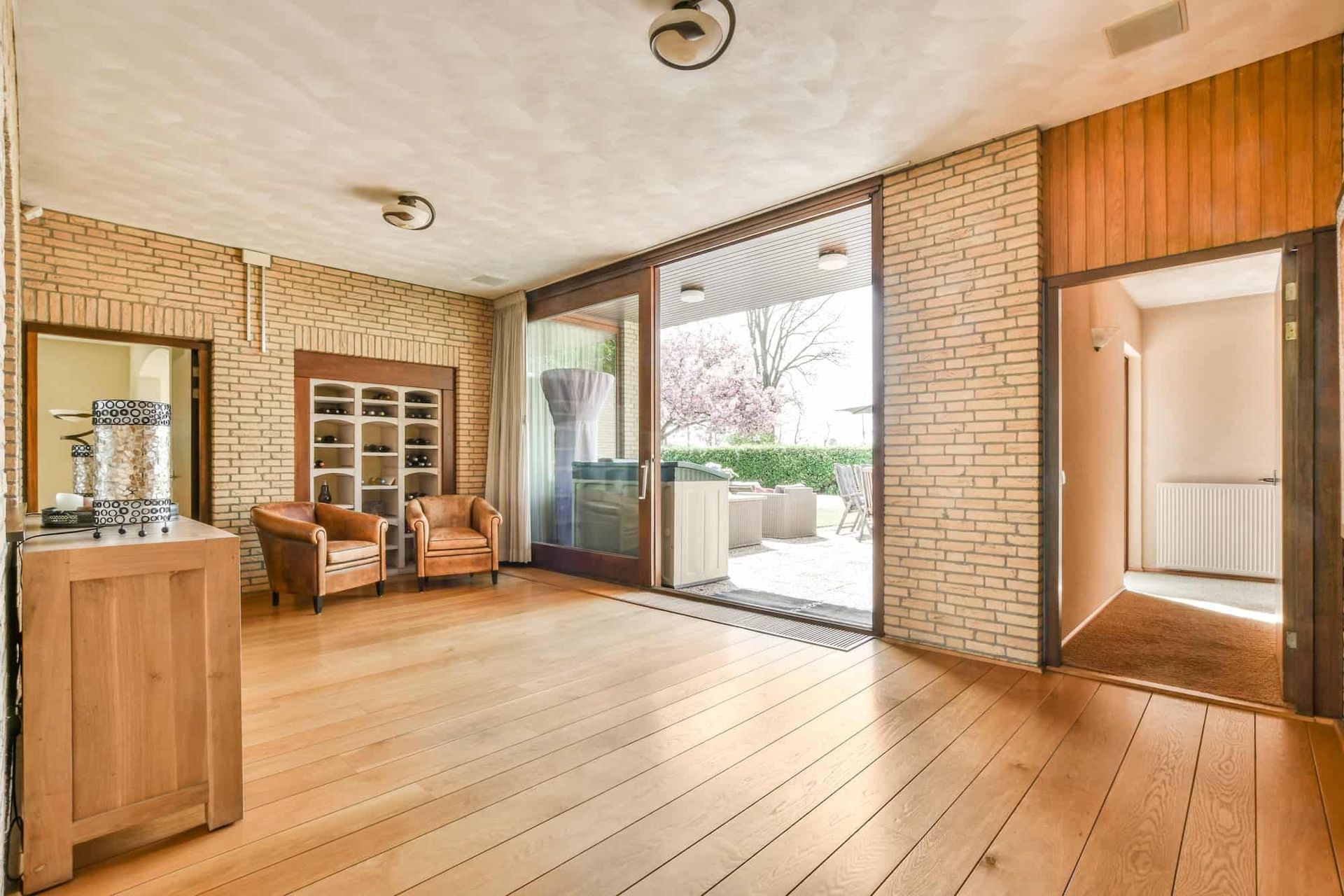 An empty living room with hardwood floors and a brick wall.