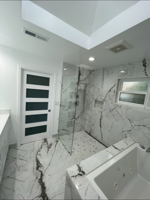 A bathroom with marble walls and a walk in shower