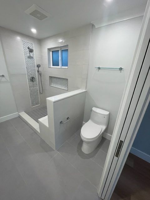 A bathroom with a toilet , shower and window