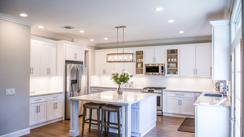 A kitchen with white cabinets and a large island in the middle.