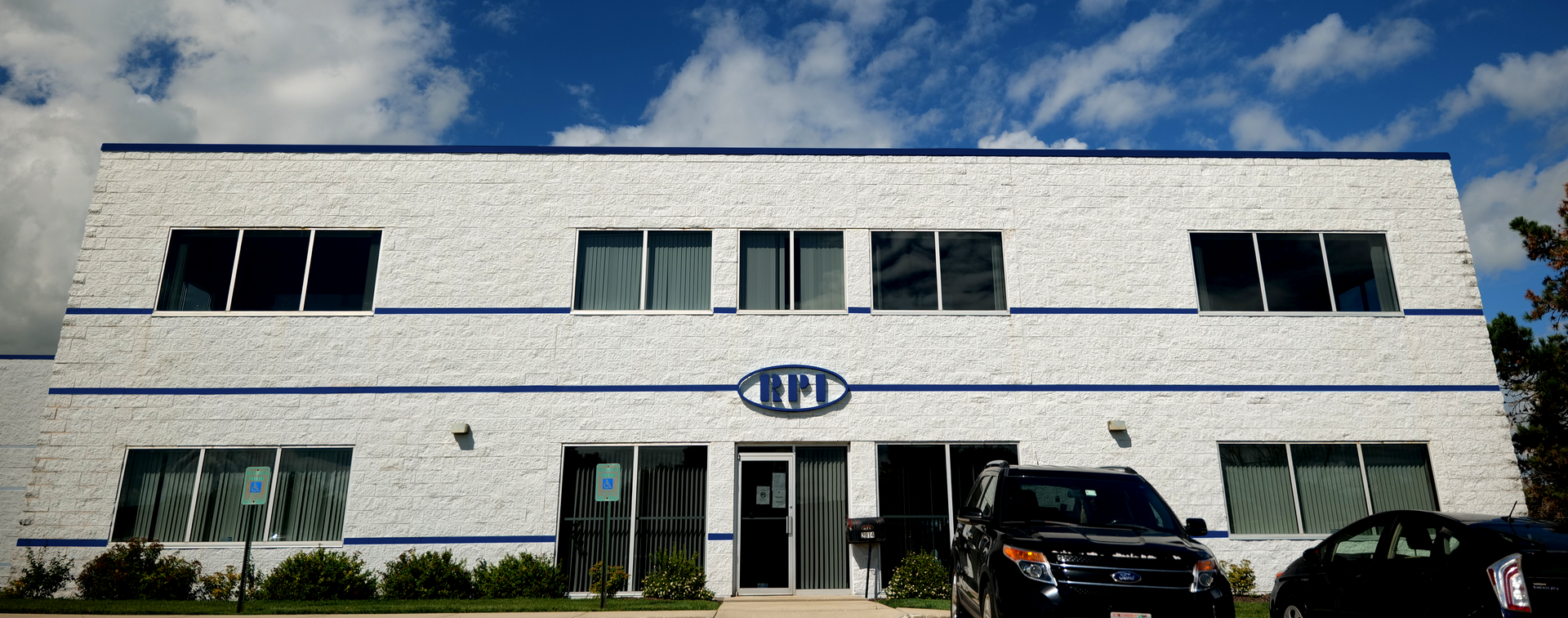 A large white building with a blue trim and a car parked in front of it.