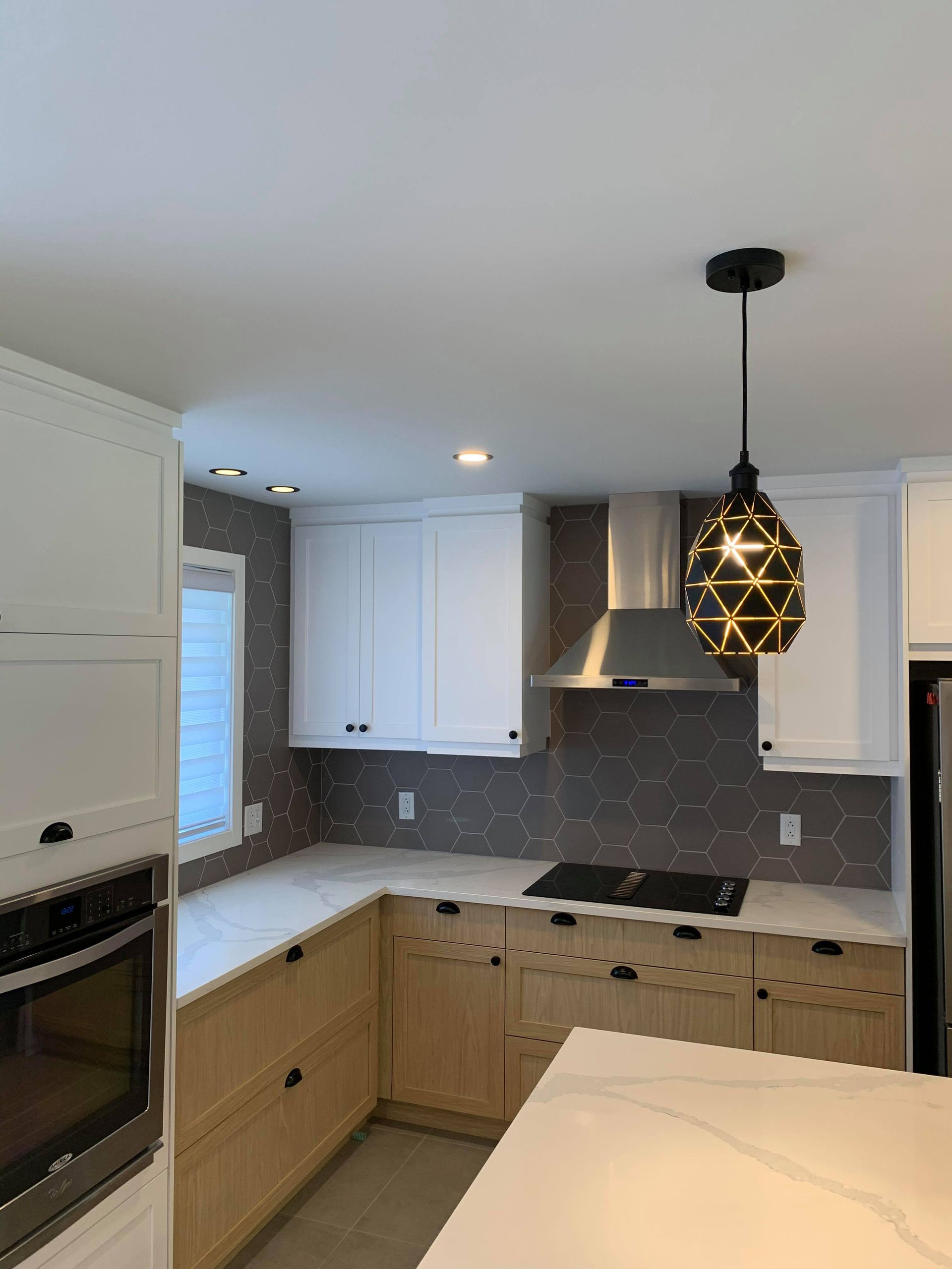 Une cuisine avec des armoires blanches, des appareils en acier inoxydable et une suspension suspendue au plafond.