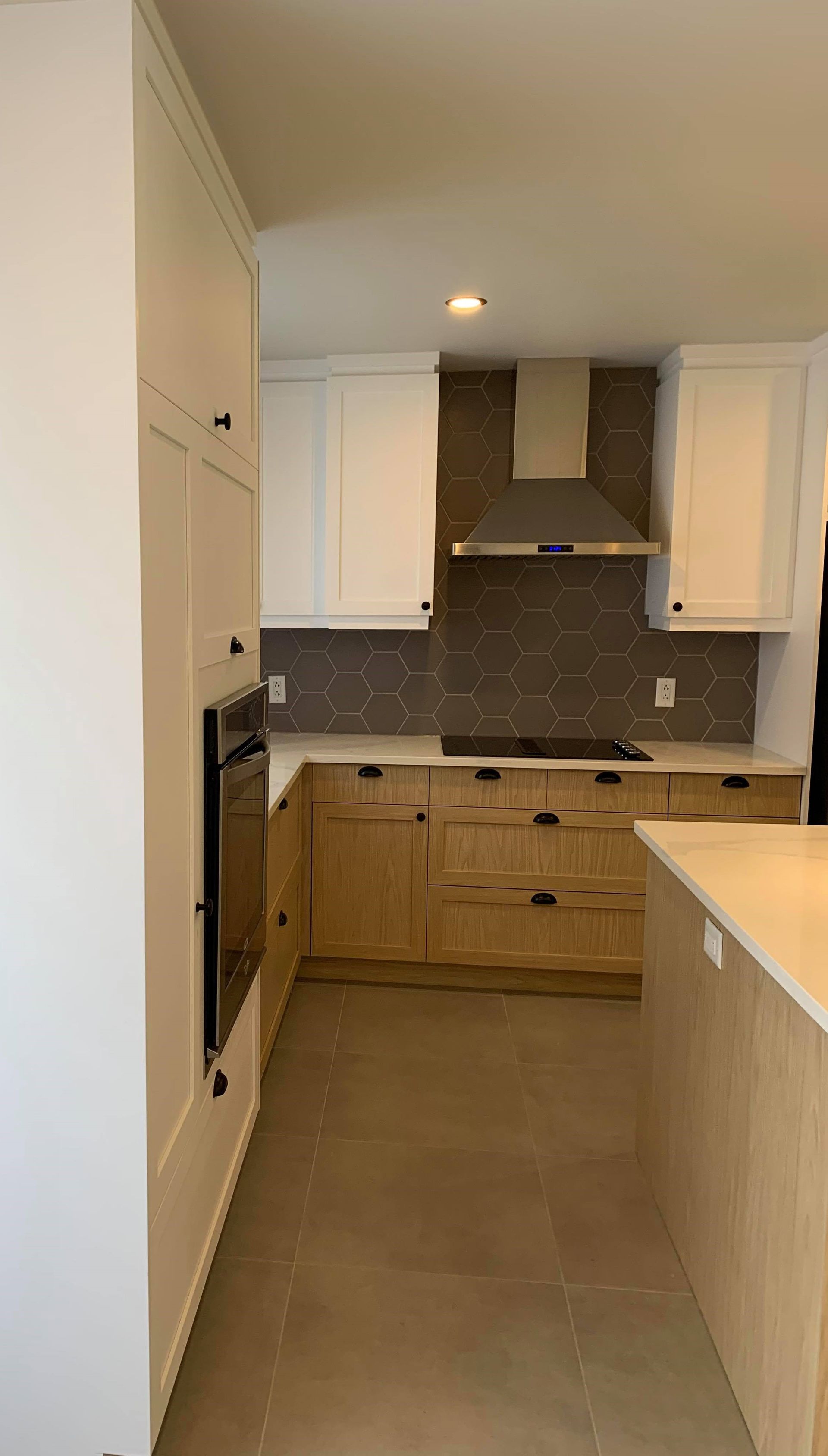 Une cuisine avec des armoires blanches, des armoires en bois, une cuisinière et une hotte.