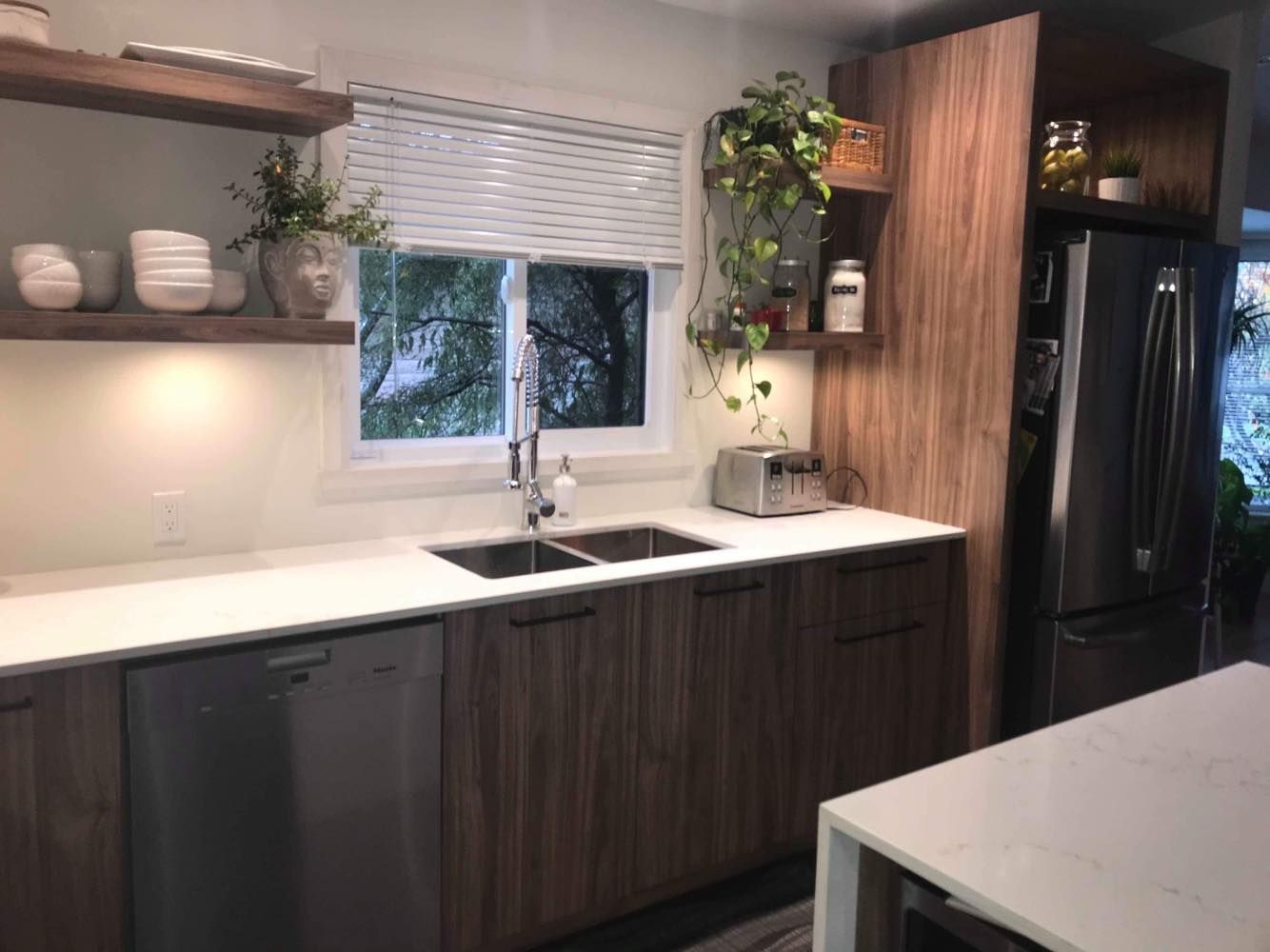 Une cuisine avec un évier, un lave-vaisselle, un réfrigérateur et une table.