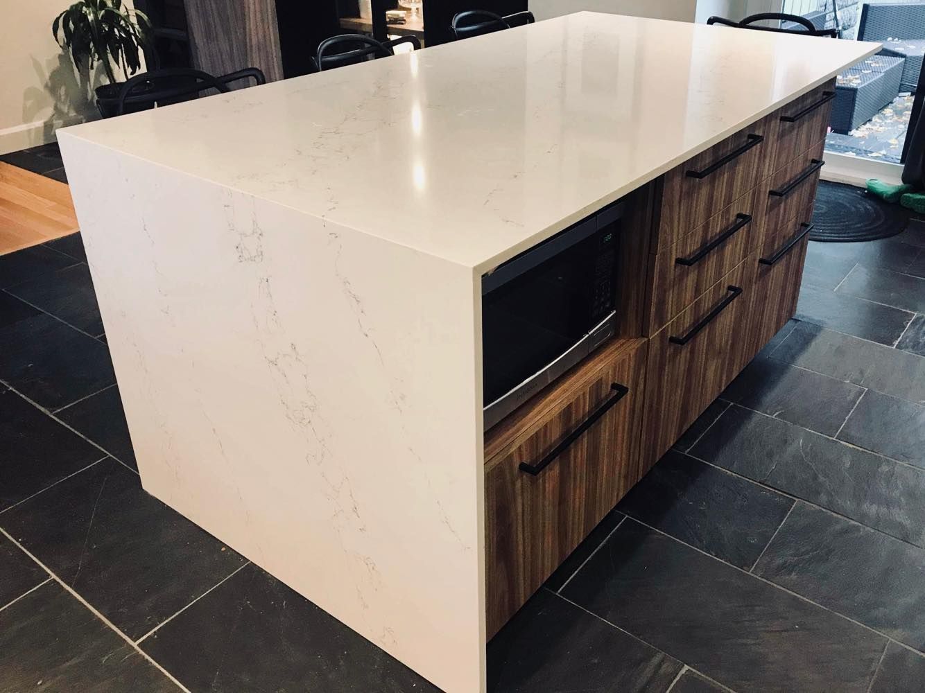 Un îlot de cuisine avec un comptoir blanc et des armoires en bois.