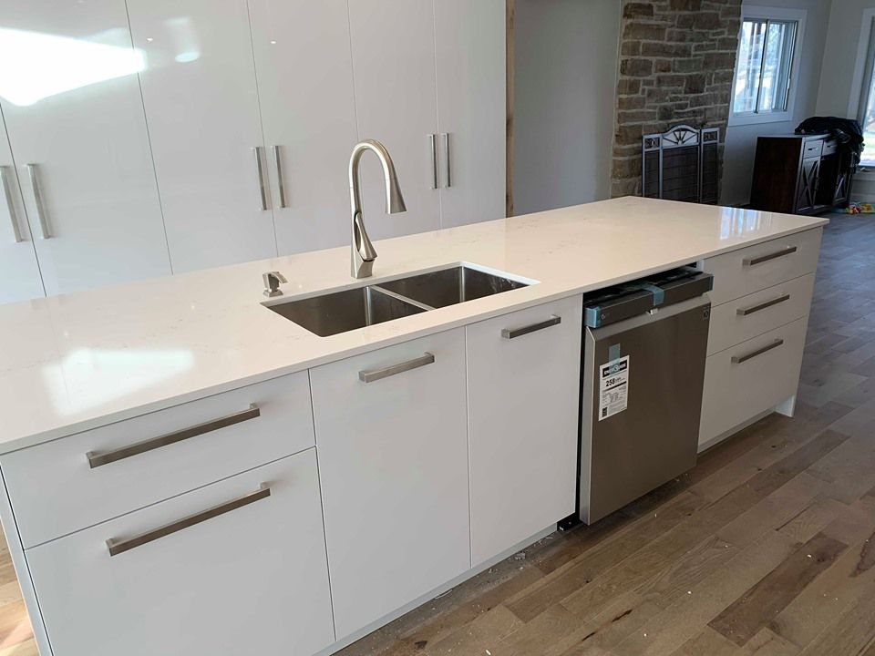 Une cuisine avec des armoires blanches, un évier en acier inoxydable et un lave-vaisselle.