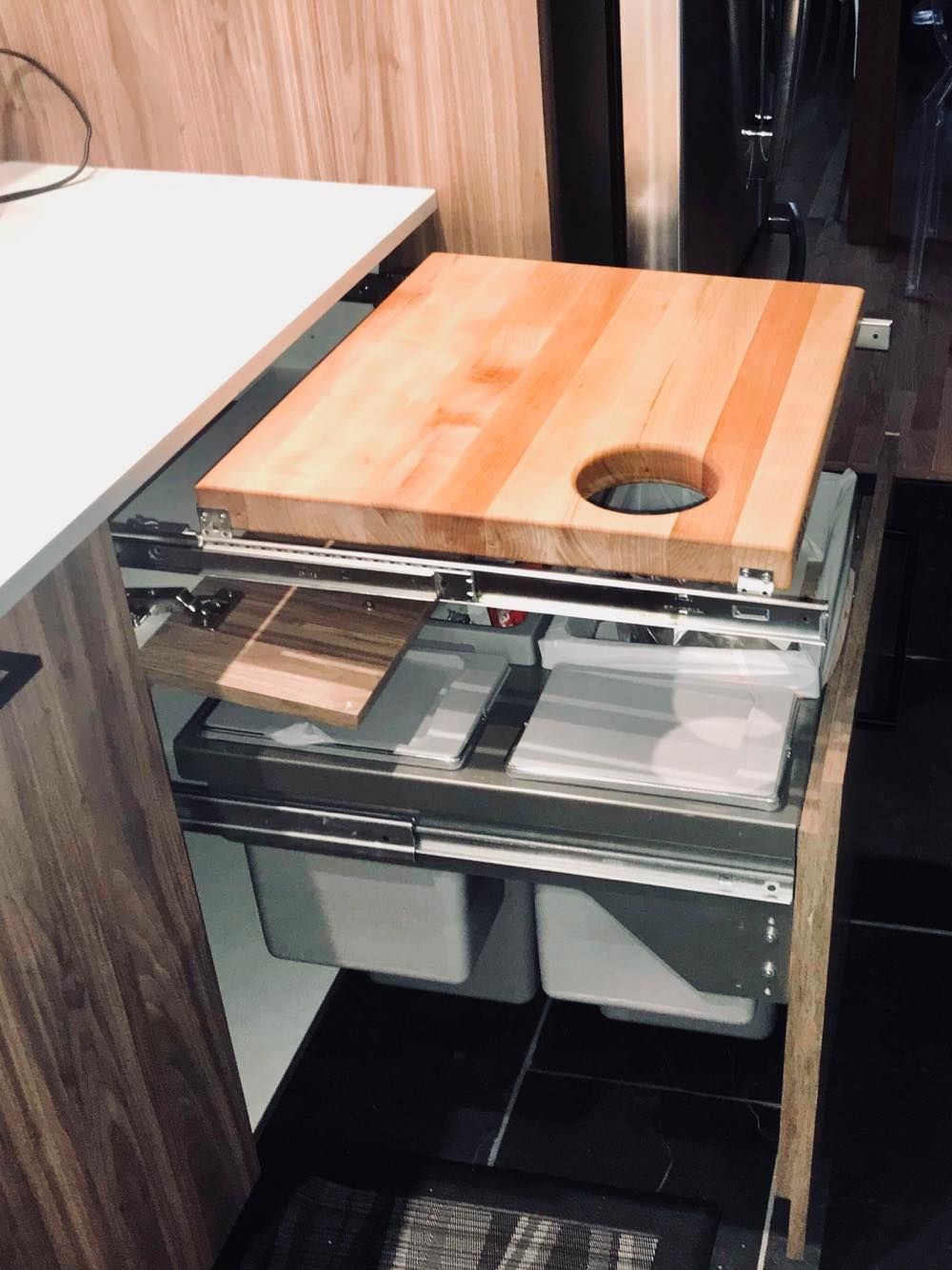 Une planche à découper en bois est sortie d'un tiroir dans une cuisine.