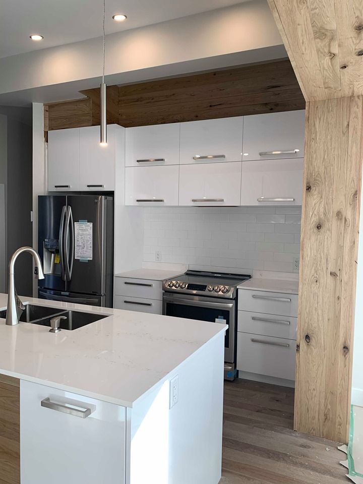 Une cuisine avec des armoires blanches, une cuisinière, un réfrigérateur et un évier.