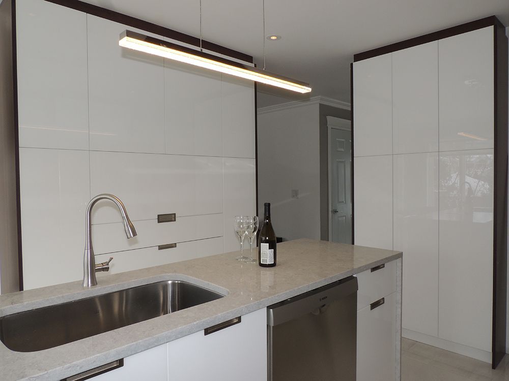 Une cuisine avec un évier et une bouteille de vin sur le comptoir.