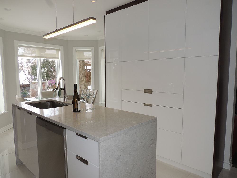 Une cuisine avec des armoires blanches et un grand îlot avec une bouteille de vin dessus.