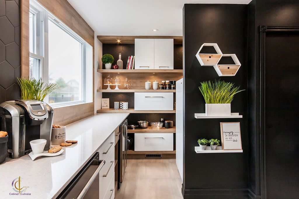 Une cuisine avec des murs noirs et des armoires et étagères blanches