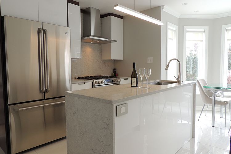 Une cuisine avec des appareils en acier inoxydable et une bouteille de vin sur le comptoir.