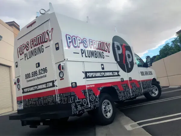A pop 's family plumbing truck is parked in a parking lot