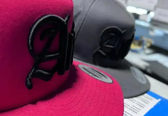 A pink and a gray hat are sitting next to each other on a table.