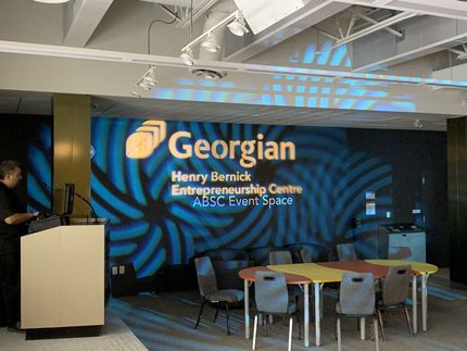 Georgian College event space with logo, podium, tables, and chairs.