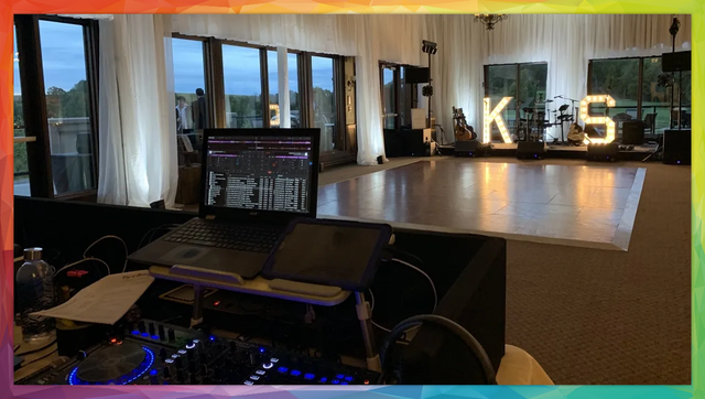 DJ setup with laptop and mixer, dance floor, lit initials 