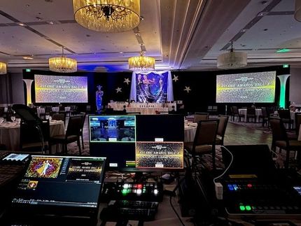 Event setup with screens, stage, and AV equipment in a ballroom.