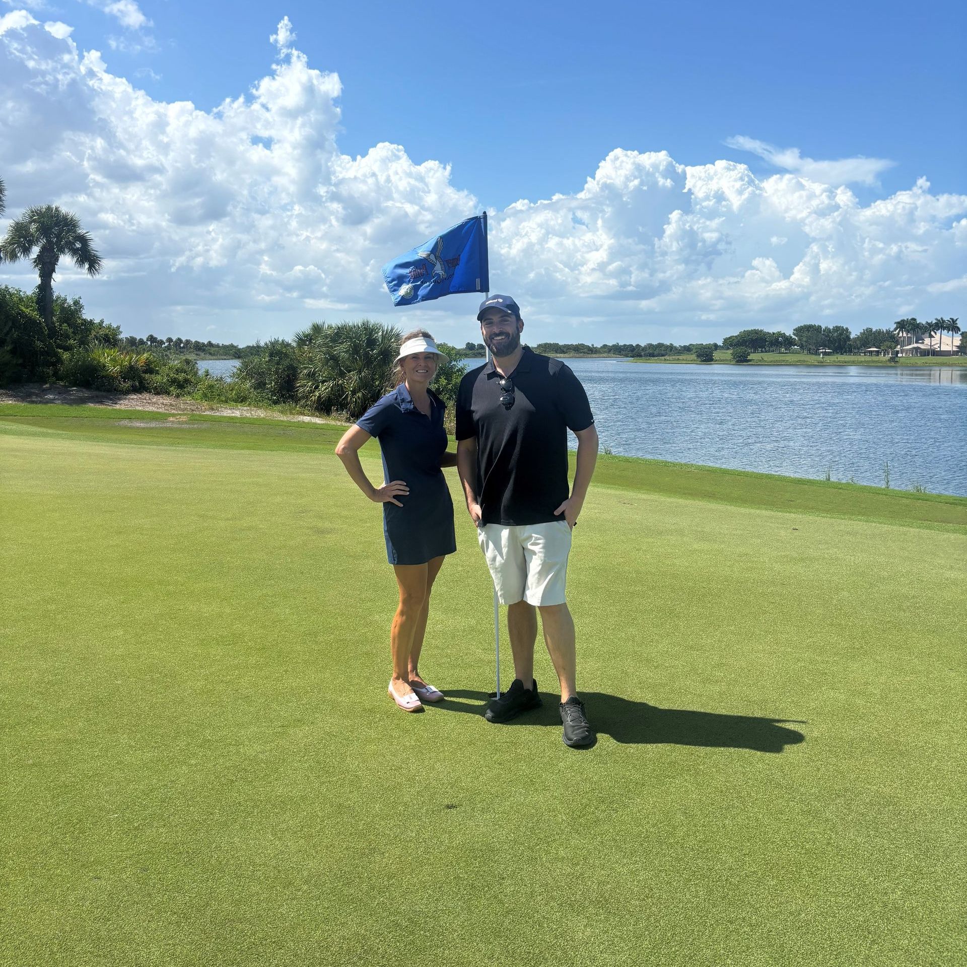 A man and a woman are posing for a picture on a golf course.