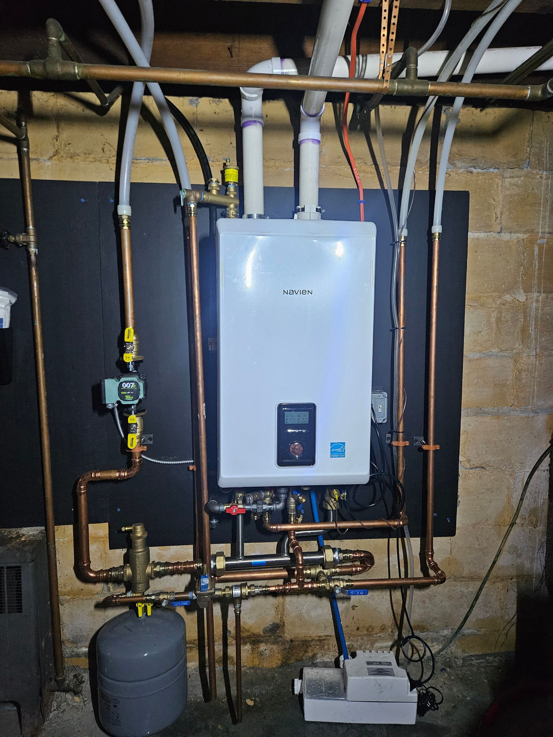 White wall-mounted water heater with copper pipes in a basement.