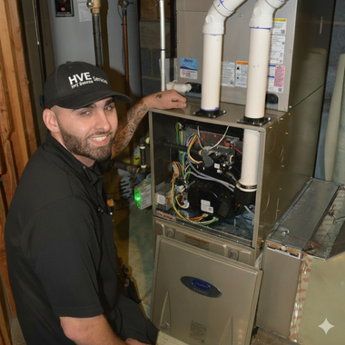Man in black uniform points to furnace; indoor setting.
