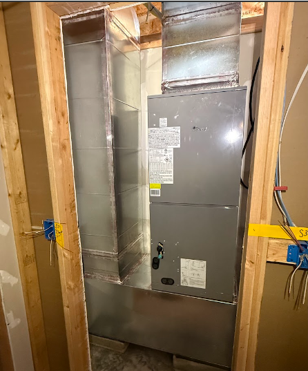HVAC unit installed inside a wooden framed enclosure, with ductwork visible above and to the left.