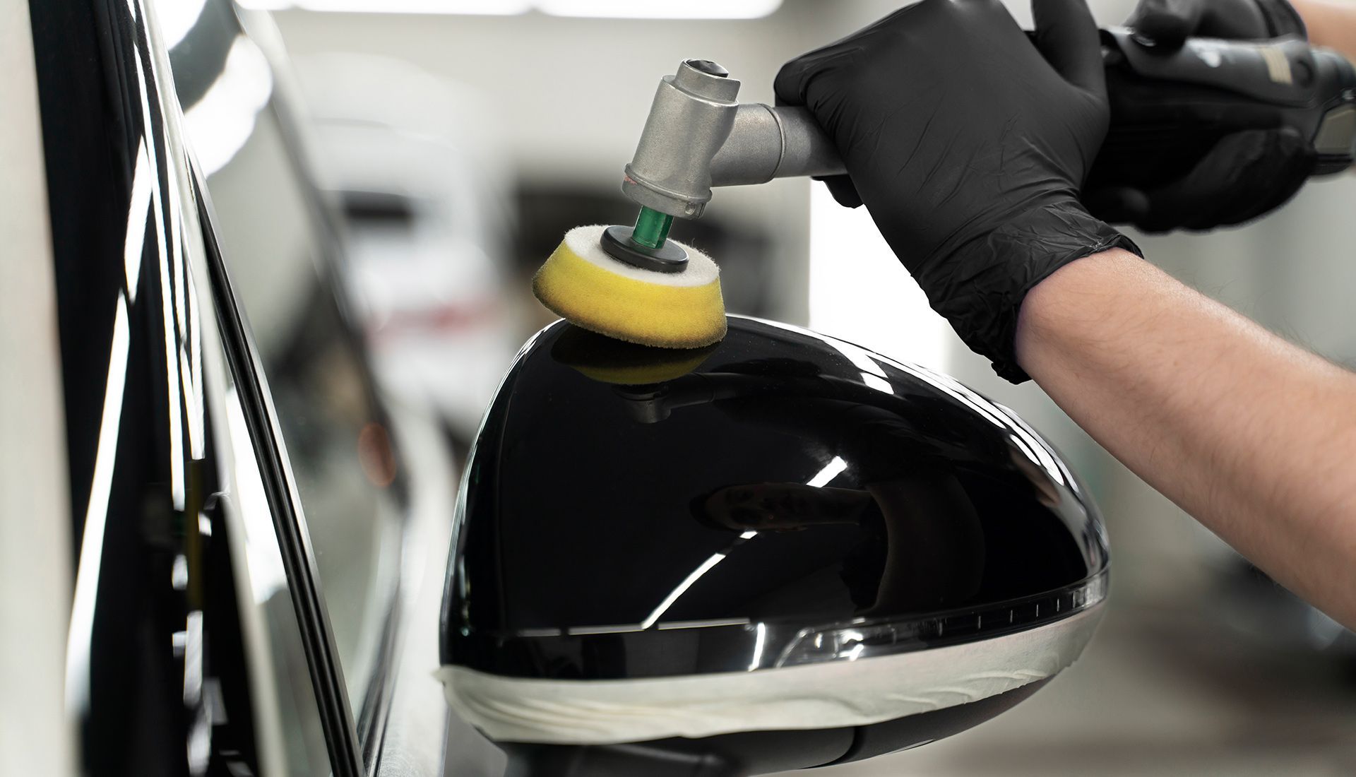 A person is polishing the side mirror of a car.