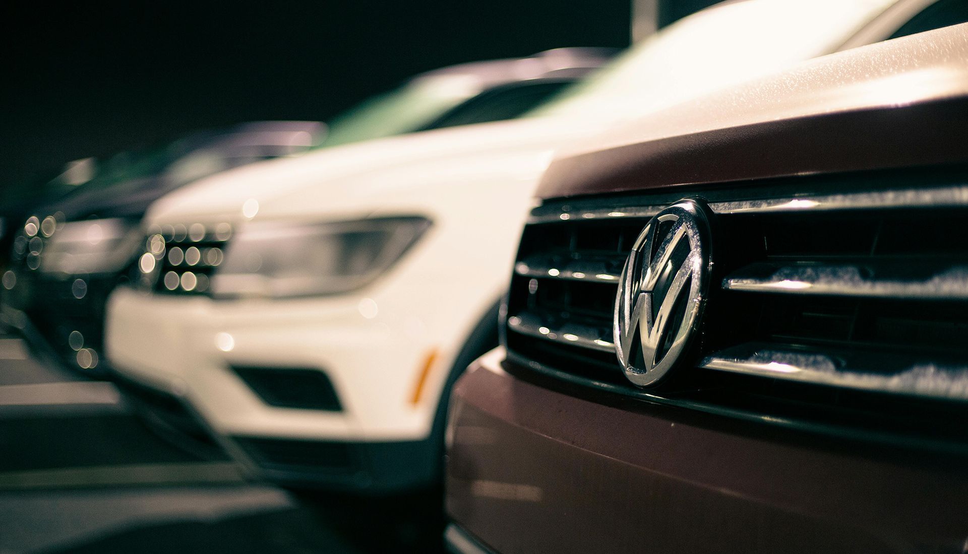A row of volkswagen cars are parked next to each other in a parking lot.