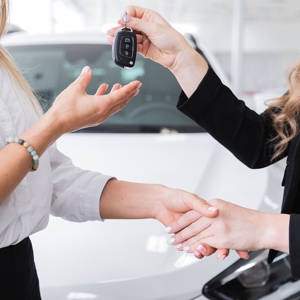 A woman is handing a car key to another woman.