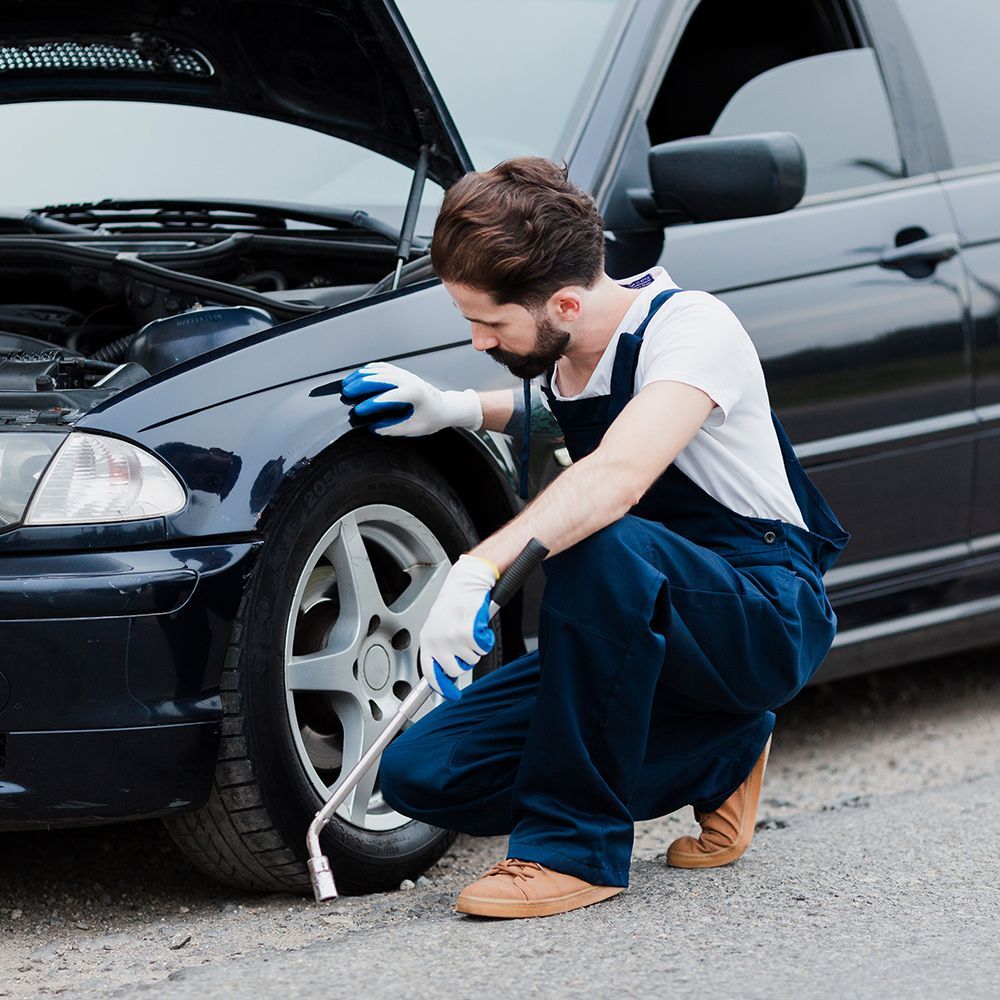 A man is changing a tire on a black car.