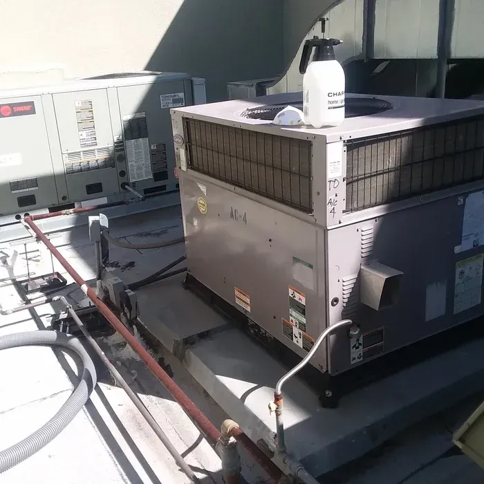 HVAC units on a rooftop. A spray bottle and a white cap sit on top of the front unit.