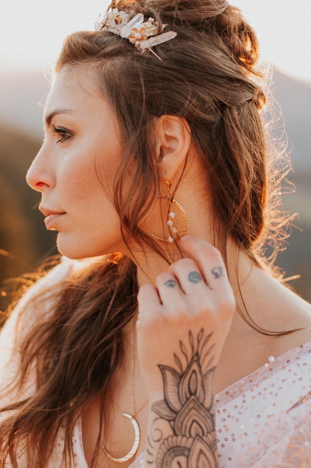 Eine Frau mit einem Tattoo auf ihrem Arm trägt eine Krone und Ohrringe .