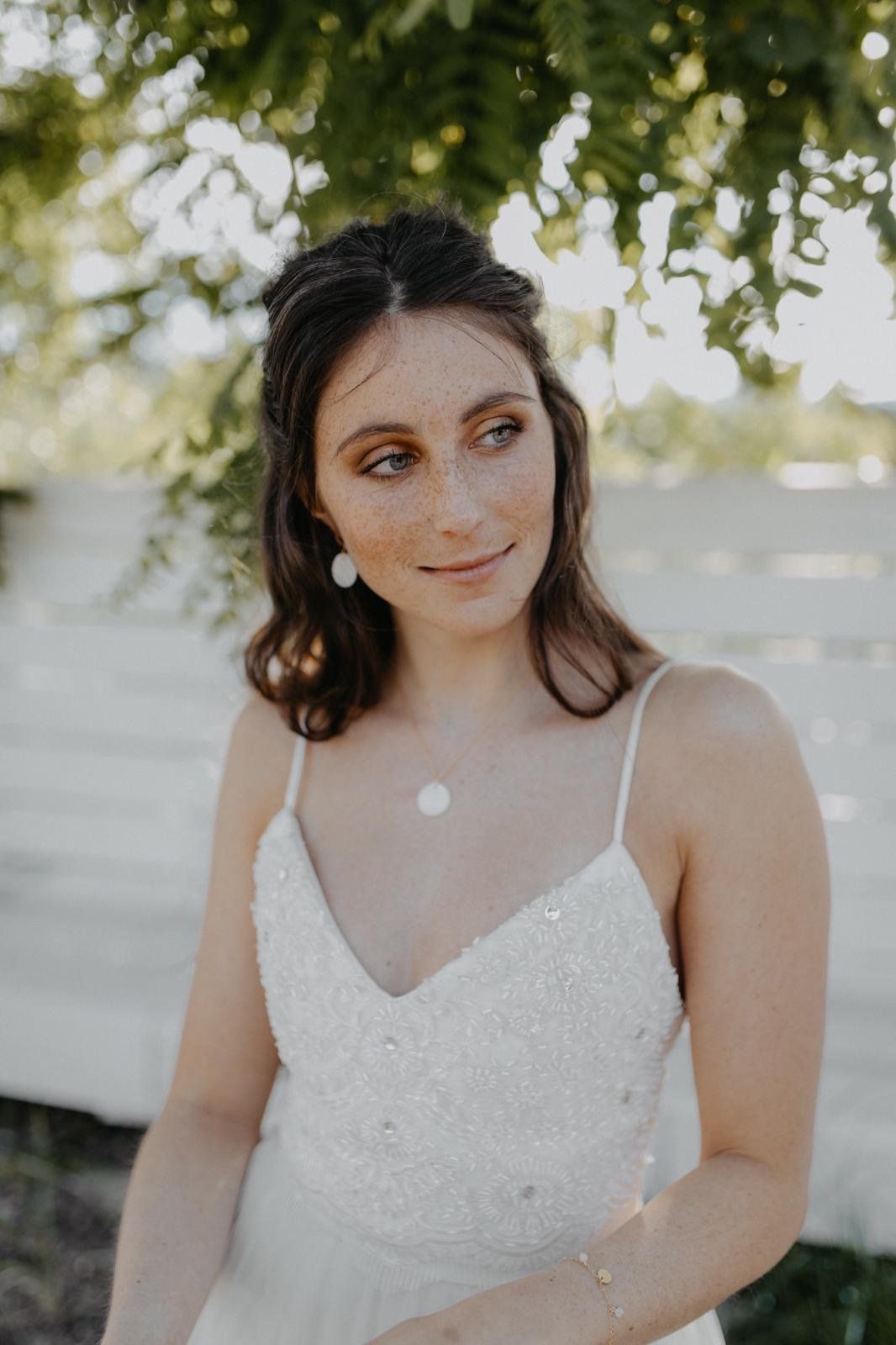Eine Frau in einem weißen Kleid steht vor einem Baum .