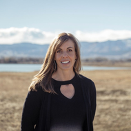 Blonde woman smiling in a white t-shirt, looking towards the viewer.