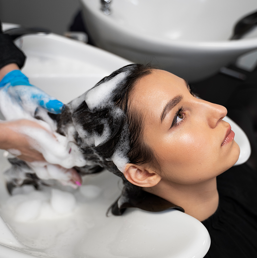 Woman getting her hair washed in a salon, receiving head massage with soapy shampoo.