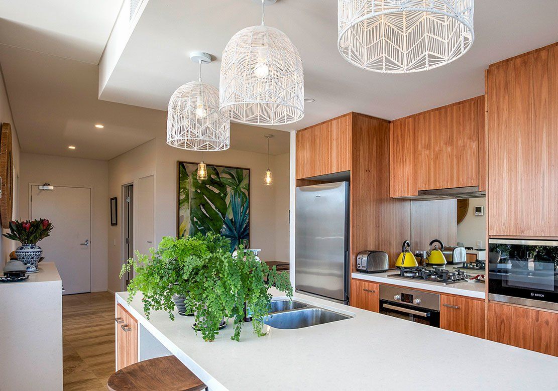 Modern Kitchen With Wooden Cabinets And Pendant Lights — Electricians in Coffs Harbour, NSW