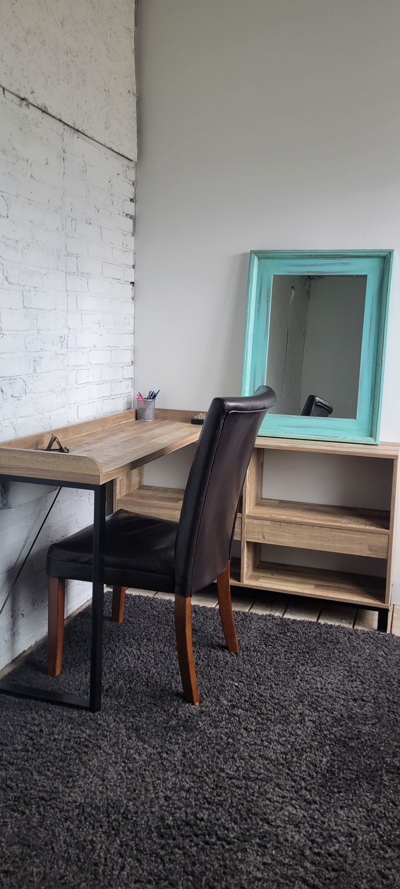 A room with a desk , chair and mirror.