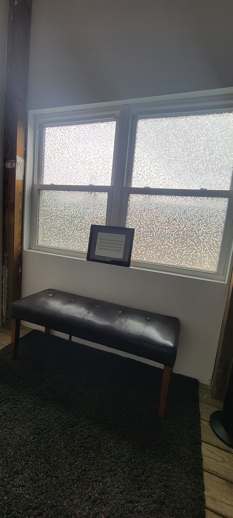 A black bench is sitting in front of a window in a room.